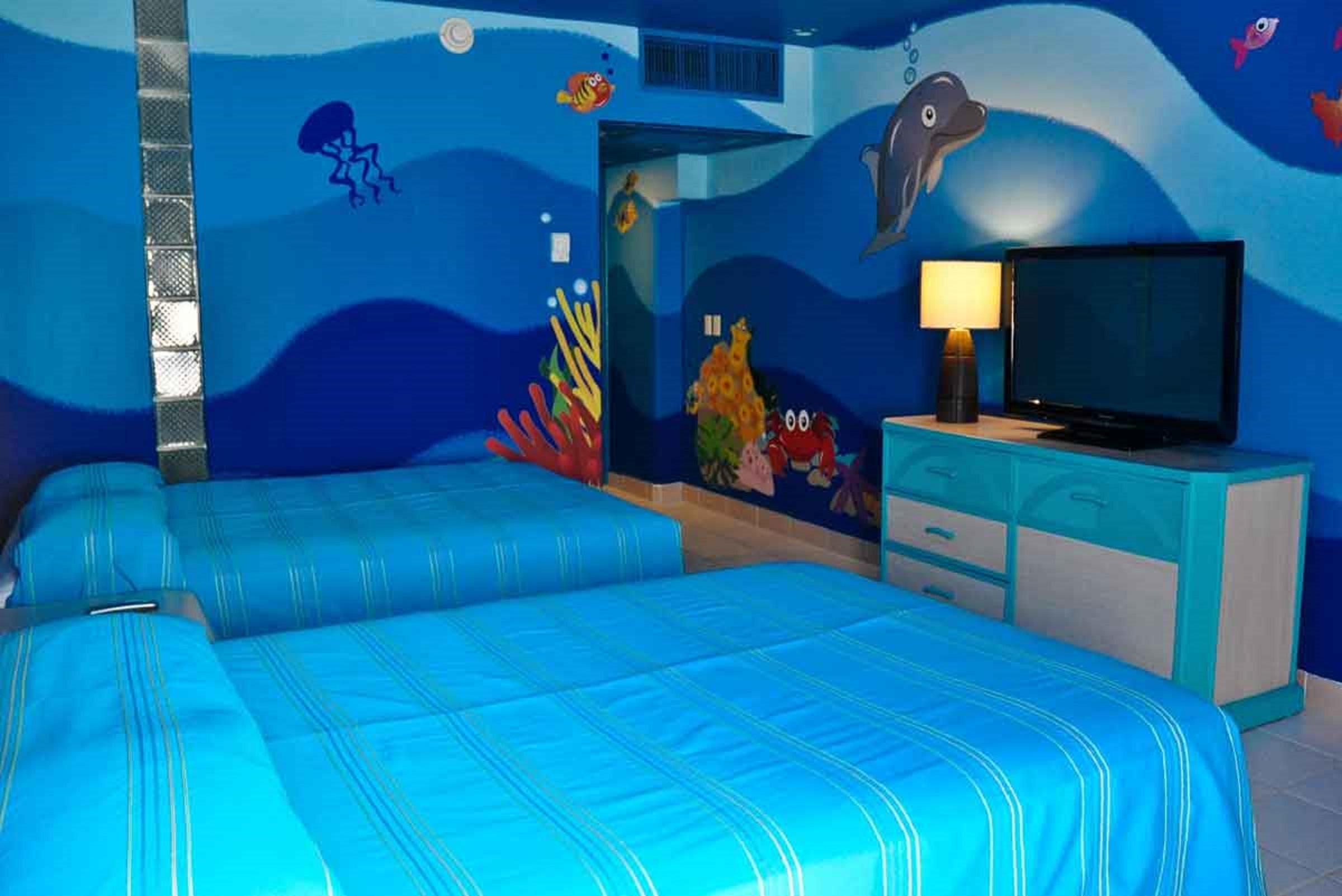 Grand Oasis Palm Hotel Cancún Exterior foto The photo shows a brightly colored hotel room with a themed underwater design. The walls are painted in various shades of blue, resembling ocean water, and feature colorful sea creatures such as fish and a dolphin. There are two beds with blue stripe